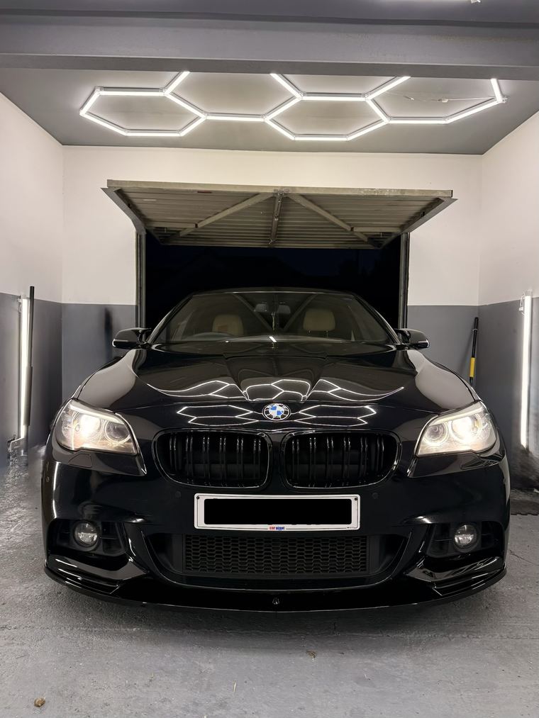 Black BMW 5 Series head-on in the bay with the roller shutter open behind it